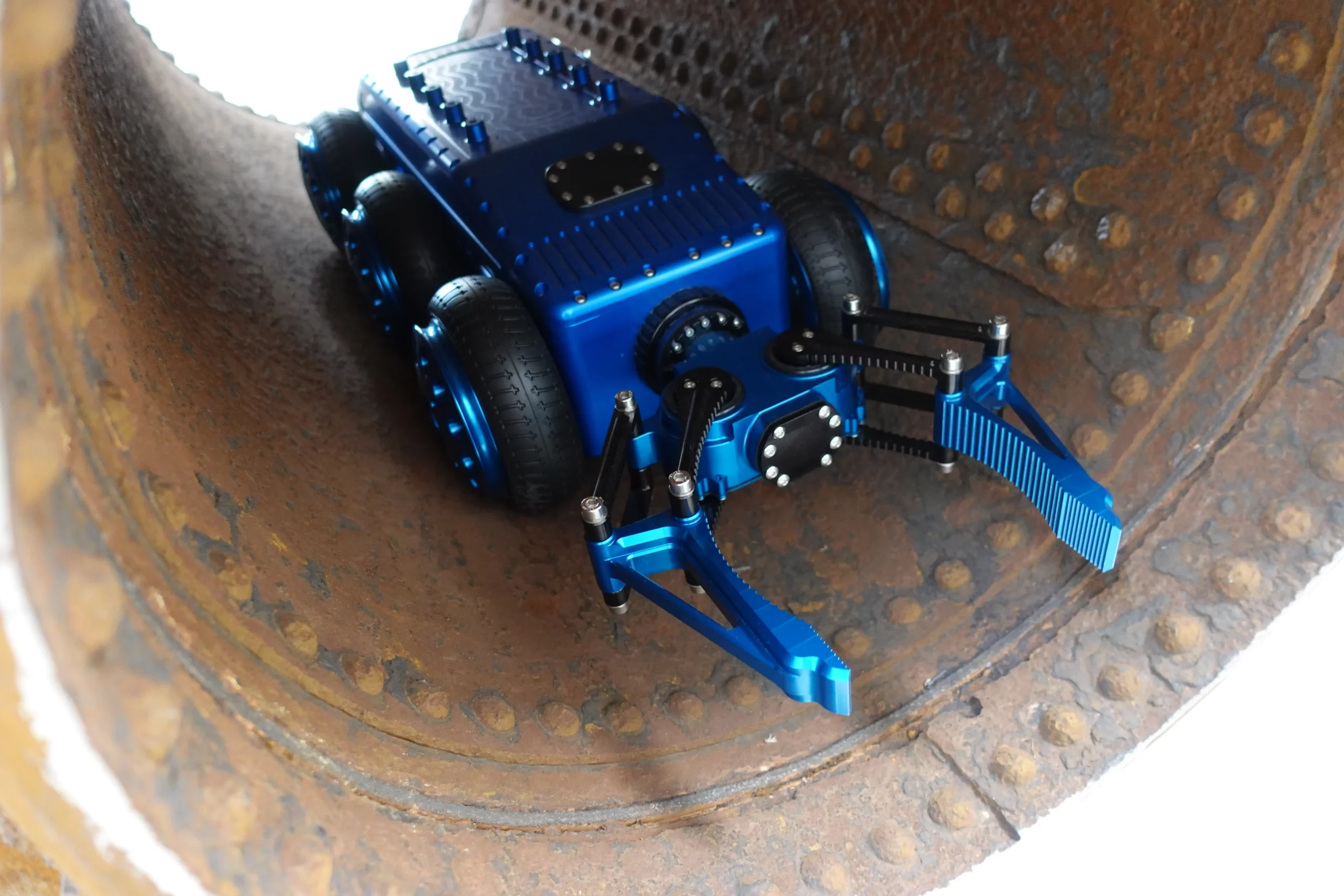 xRobot Argyros de Sfynx Industry en aluminium bleu, équipé de bras articulés d’inspection, progressant à l’intérieur d’une grande conduite industrielle rouillée pour réaliser des contrôles en environnement confiné.