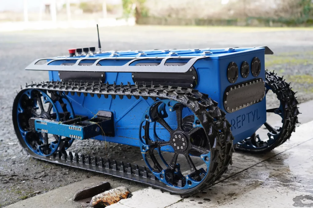 Le robot Reptyl de Sfynx Industry est présenté dans sa version originale équipée de chenilles renforcées. Conçu pour la mobilité sur terrain accidenté, ce robot tout-terrain illustre la robustesse, la précision et l’ingénierie avancée développées par l’entreprise dans le domaine de la robotique mobile.